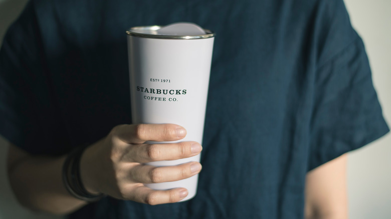 Person holding Starbucks reusable mug 