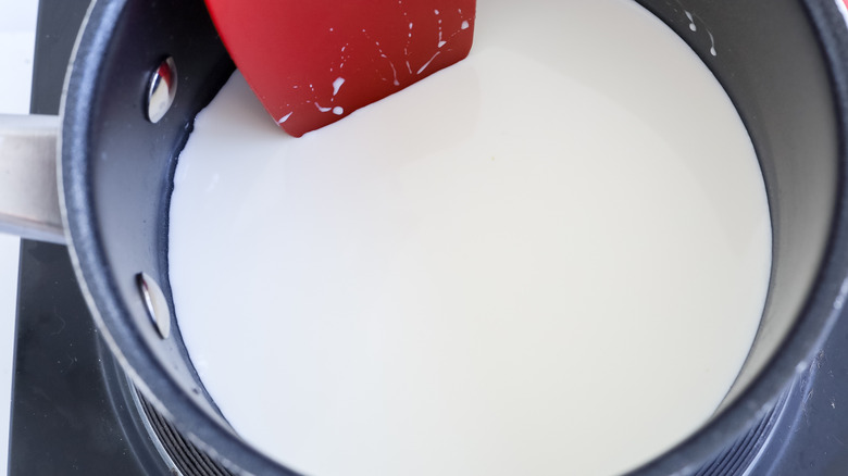 stirring cream in saucepan with rubber spatula