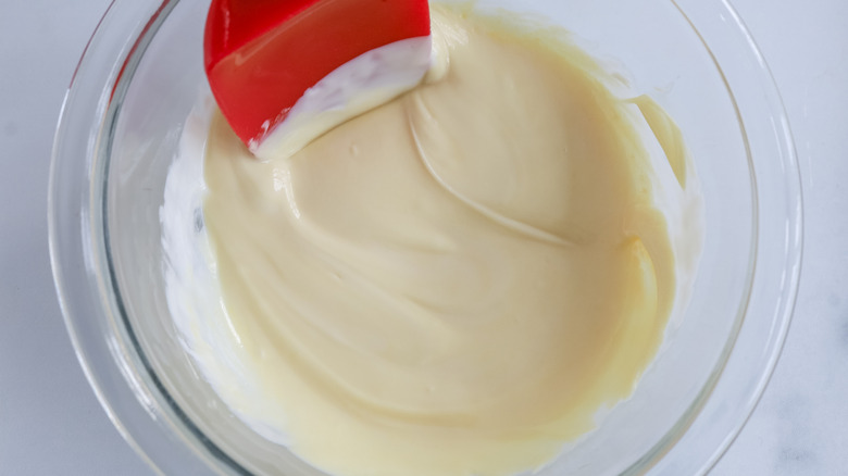 melted white chocolate in glass bowl with rubber spatula