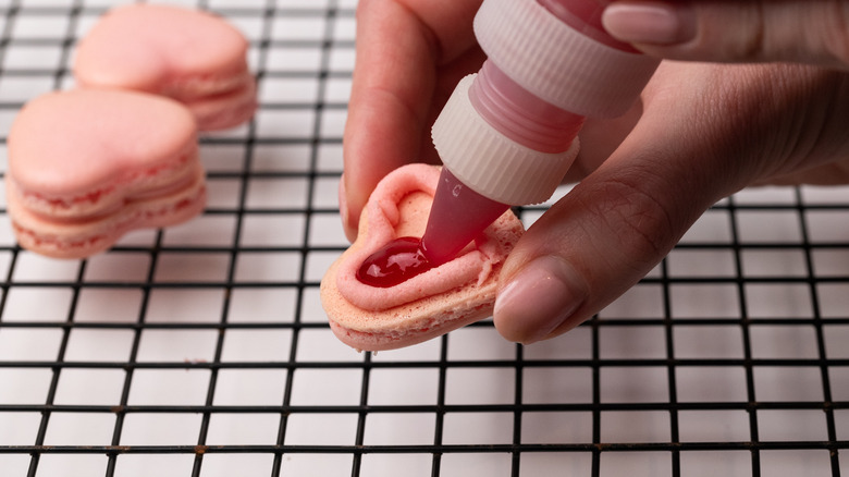 Piping jam filling into macarons 