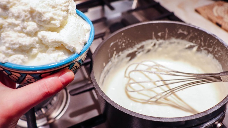 hand holding ricotta over bechamel