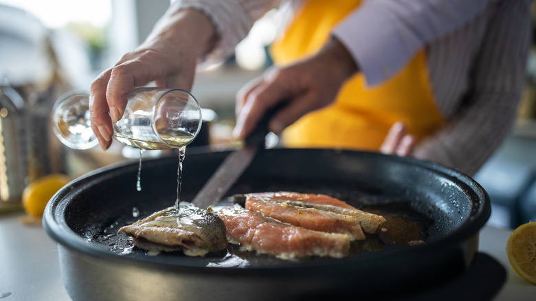 A person pours wine onto fish.