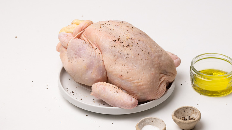 Seasoned whole raw chicken on a plate