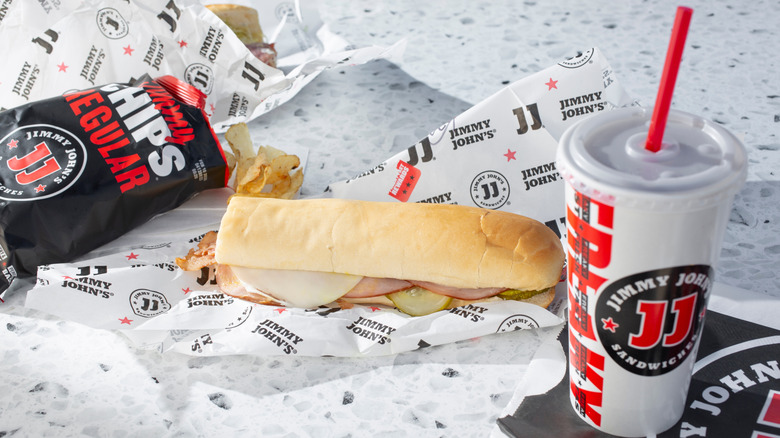 A Jimmy John's sandwich with a drink and a bag of Jimmy Chips