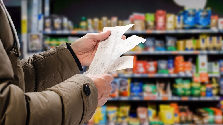 hands holding receipts in grocery store