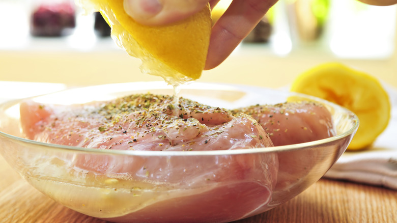 Squeezing lemon on raw chicken