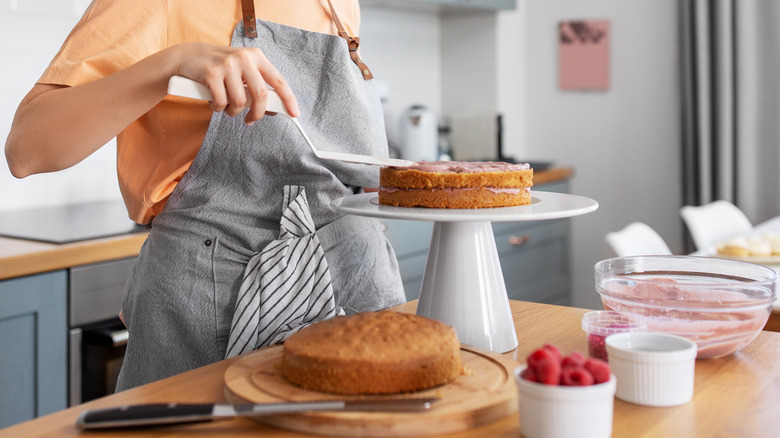 person frosting layer cake