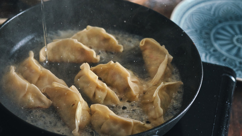 A pan of cooking potstickers