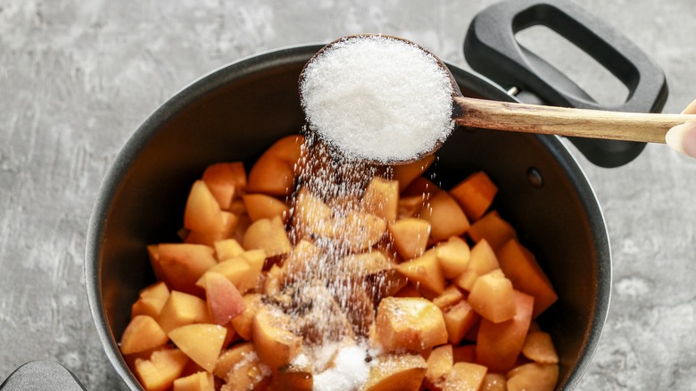 Adding sugar to fruit in a pot