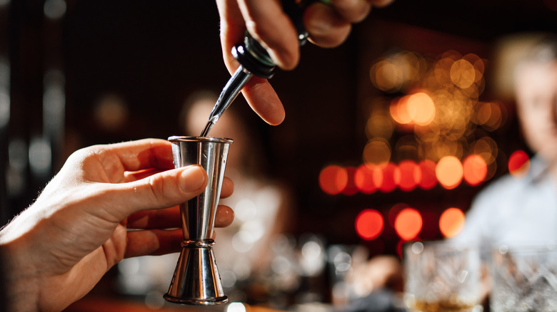 Bartender pours liquor into a jigger