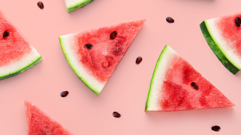 Watermelon slices and seeds on pink background