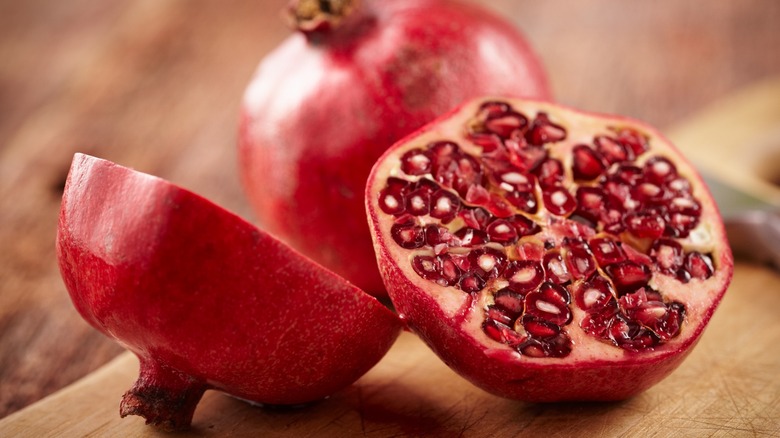 Halved pomegranate on a wooden cutting board