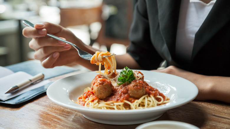 someone eating spaghetti at restaurant