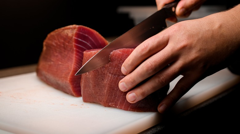 knife cutting into raw tuna