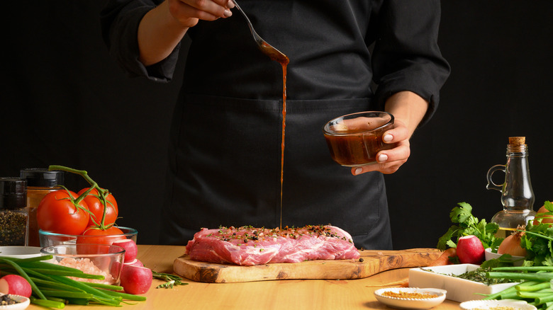 Chef pours marinade on beef