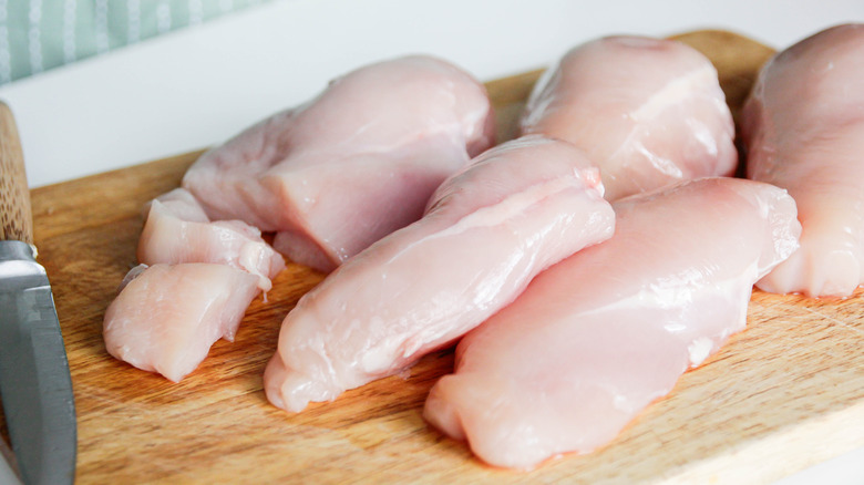 Slices of chicken breast on a wooden chopping board