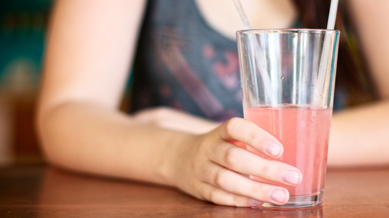 Woman sitting at a table with a pink beverage in a glass