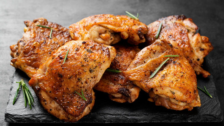 Closeup of cooked chicken thighs on slate board 