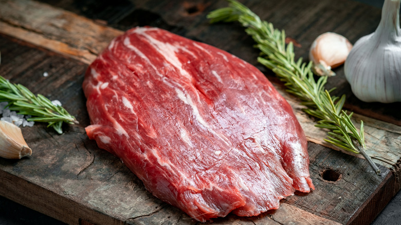 raw flank steak on cutting board 