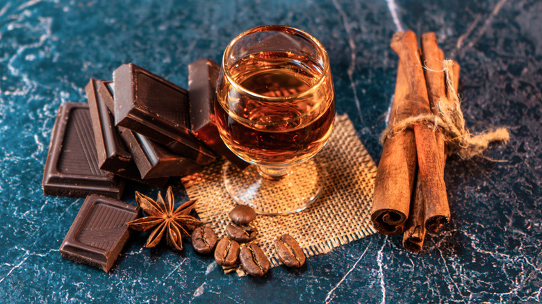 Small glass of bourbon dark chocolate squares, cinnamon, and star anise