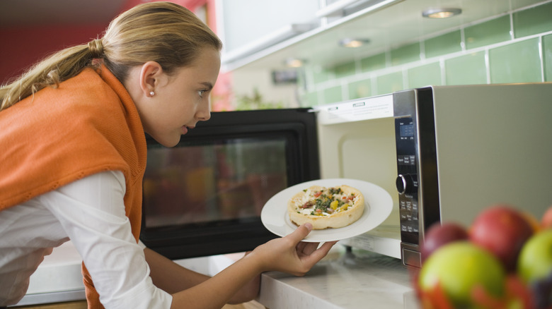 Woman putting food into microwave