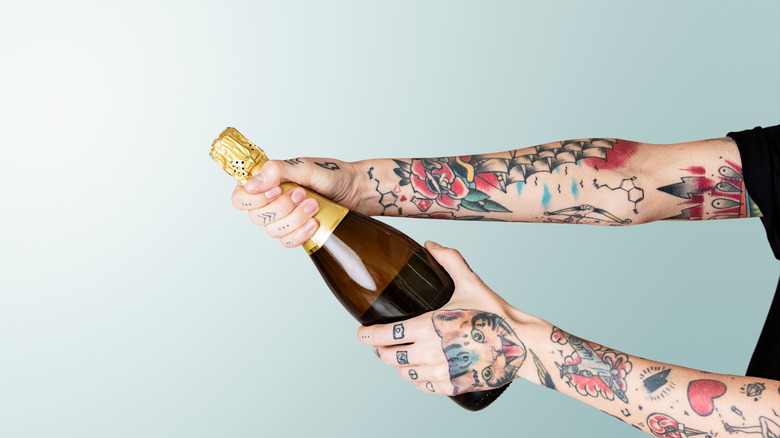 tattooed arms prosecco bottle