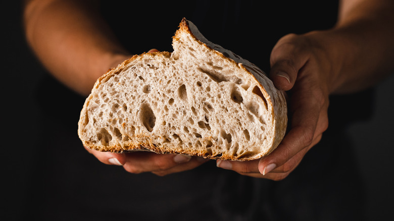 Hands holding baked bread loaf half