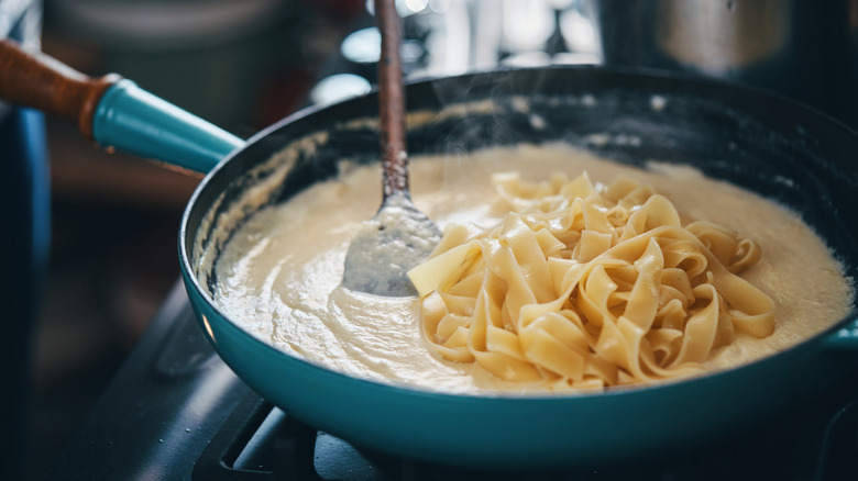 creamy alfredo sauce in a pan with fettuccine noodles