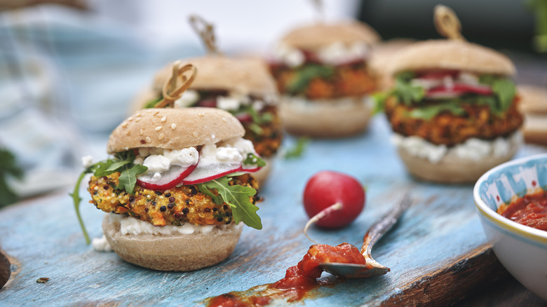 Quinoa veggie sliders on board with spoon of sauce