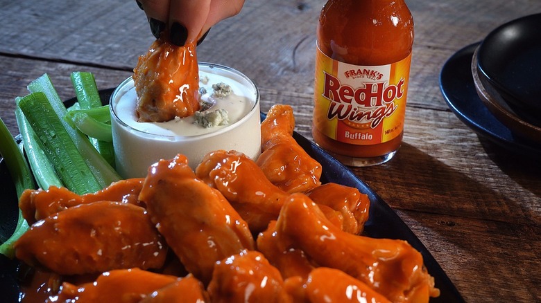 plate of wings and celery and blue cheese dip next to Frank's RedHot wing sauce bottle
