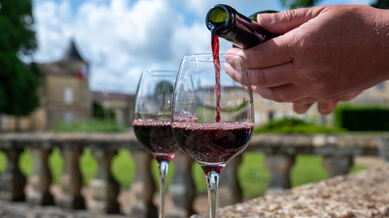 Hand pouring wine into glasses