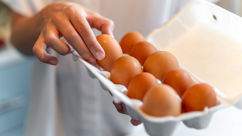 Hand reaching into egg carton