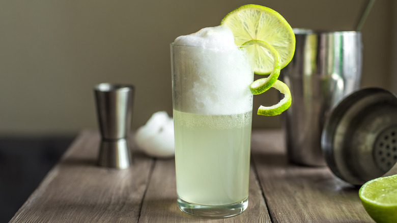 gin fizz with a thick head of egg white foam and lime wheel garnish