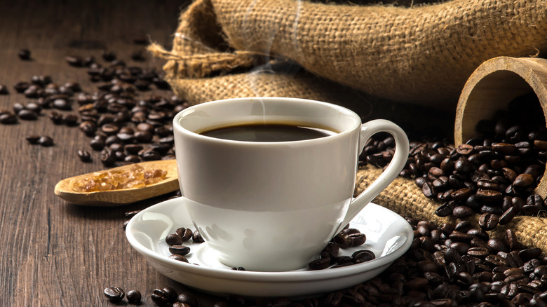 Steaming coffee cup with beans