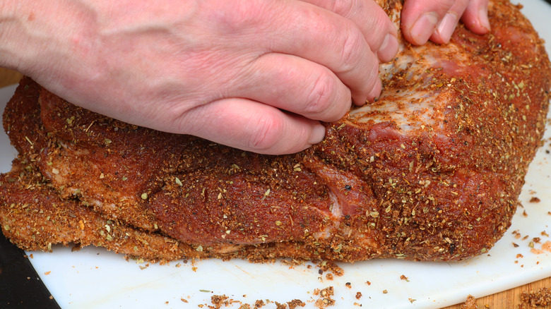 hands rubbing meat with spices