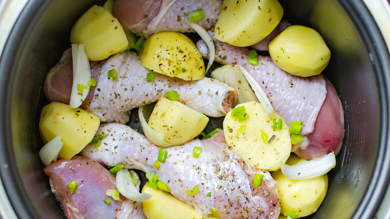 slow cooker with chicken, potatoes, and onions