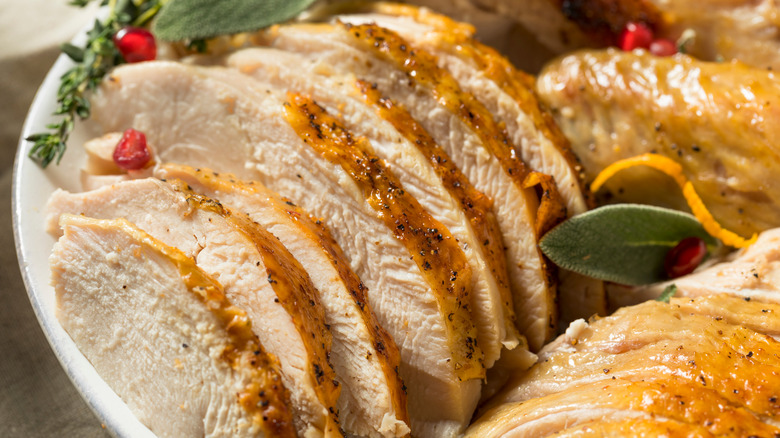 Roasted turkey sliced on a plate with herbs