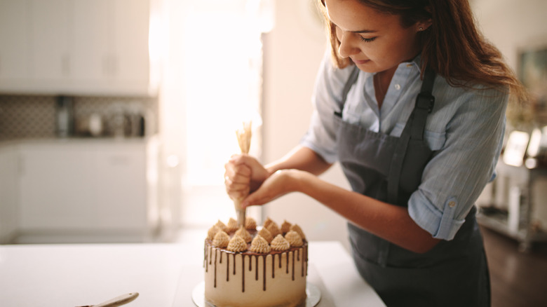 Woman decorating cake with frosting
