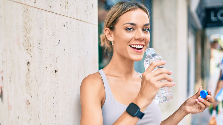 woman drinking from plastic water bottle