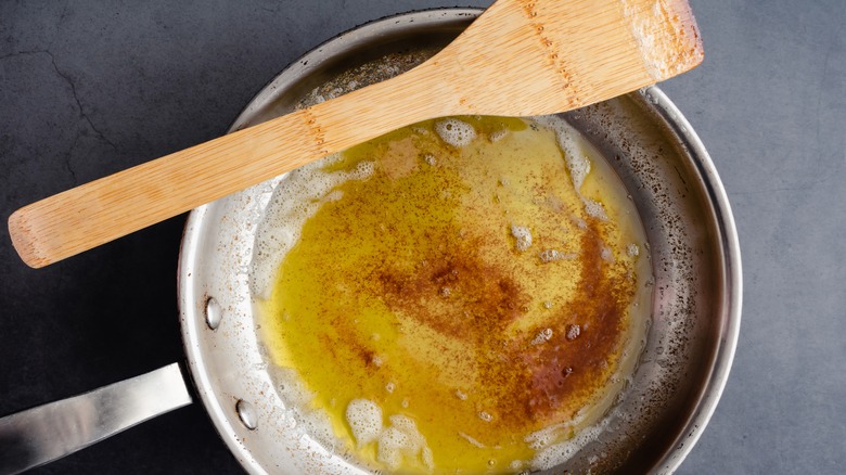 Skillet of brown butter with wooden spatula