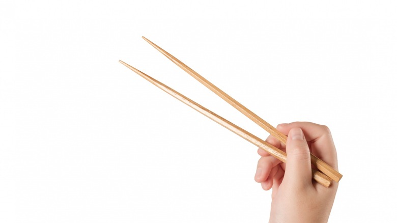 hand holding wooden chopsticks