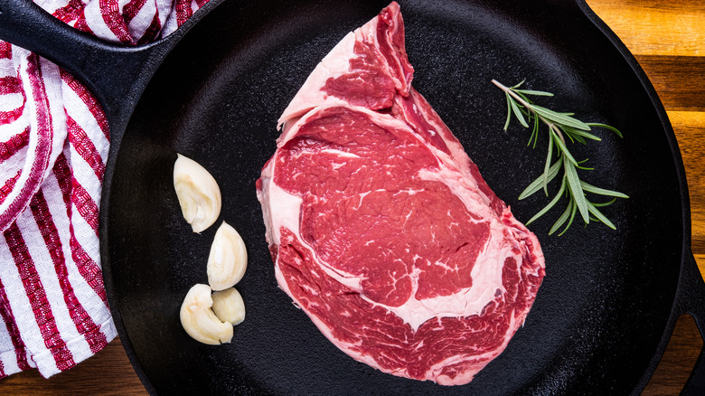 raw ribeye steak in cast iron skillet