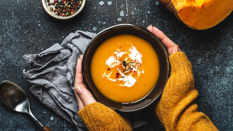 Hands holding bowl of soup