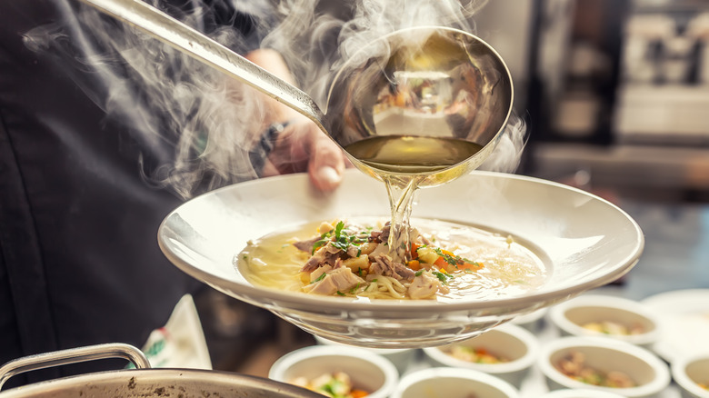 ladling broth into a bowl of soup