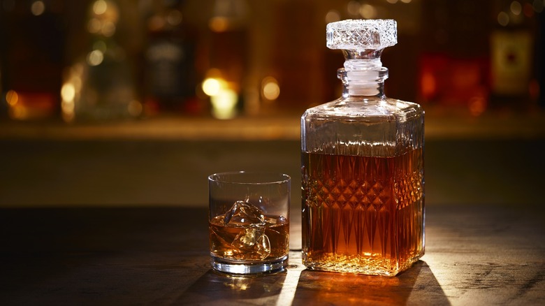 A glass of bourbon and decanter on a bar top