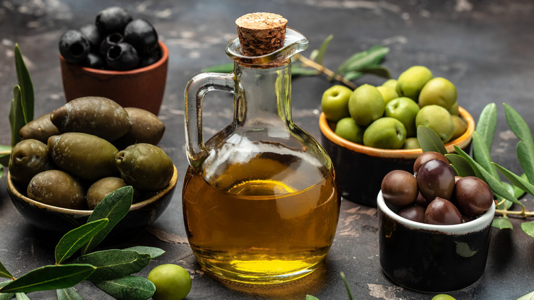 different types of olives surrounding olive oil