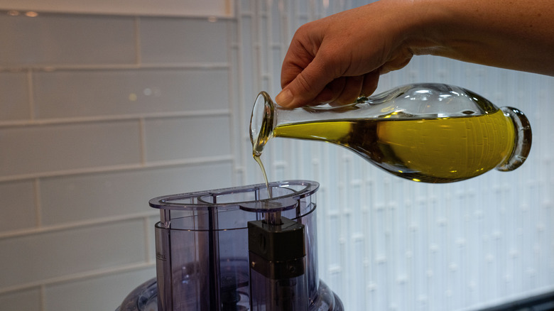 pouring olive oil into a food processor