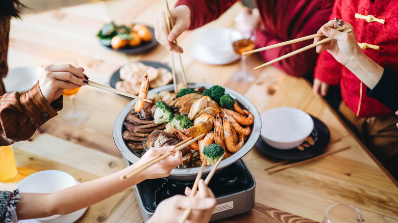 People taking food from platter with chopsticks