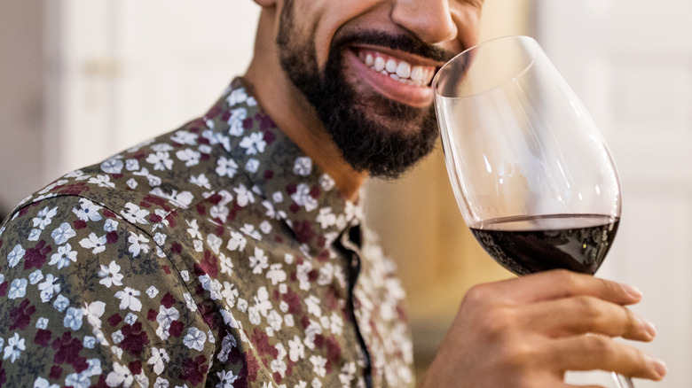 man smiling and drinking red wine