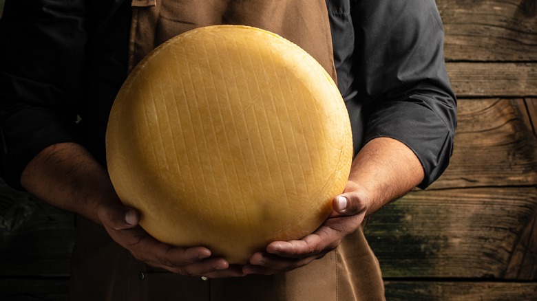 Man holding big cheese wheel